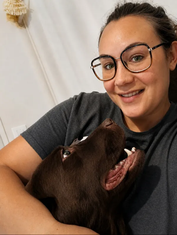 Lucie, souriante, serre Hot dans ses bras ; la chienne lève la tête vers elle